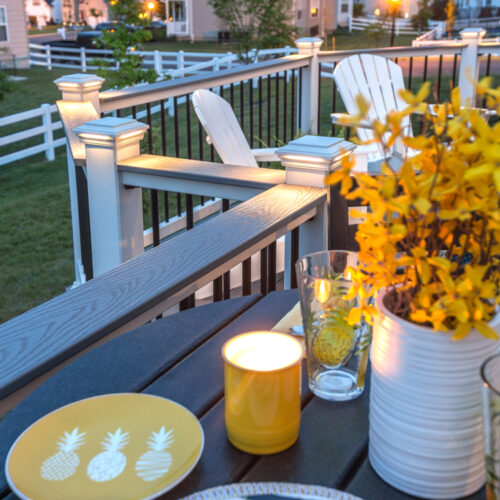 Close-up of a functional cocktail rail on a custom deck featuring a drink and candle, highlighting the wide top-rail design.
