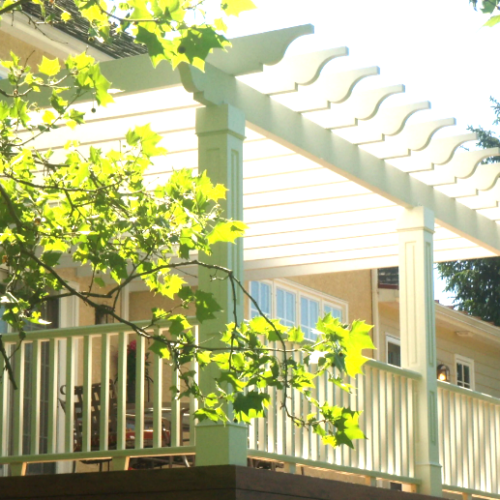 Custom white vinyl pergola with stone pillar bases installed on a backyard patio in Dagsboro, DE