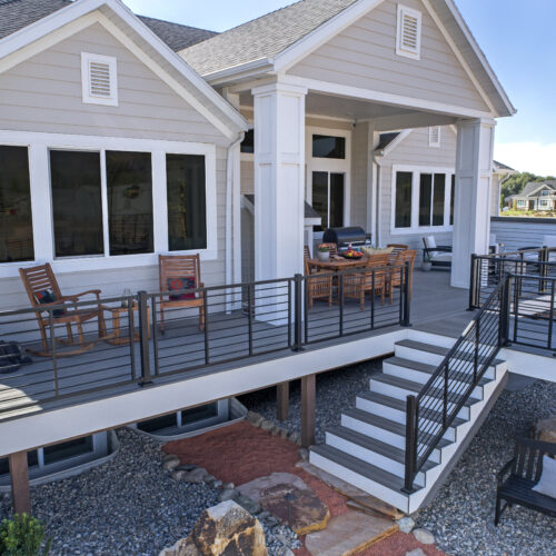 Modern Trex Island Mist composite deck featuring black Signature rod railings overlooking a coastal Delaware landscape.
