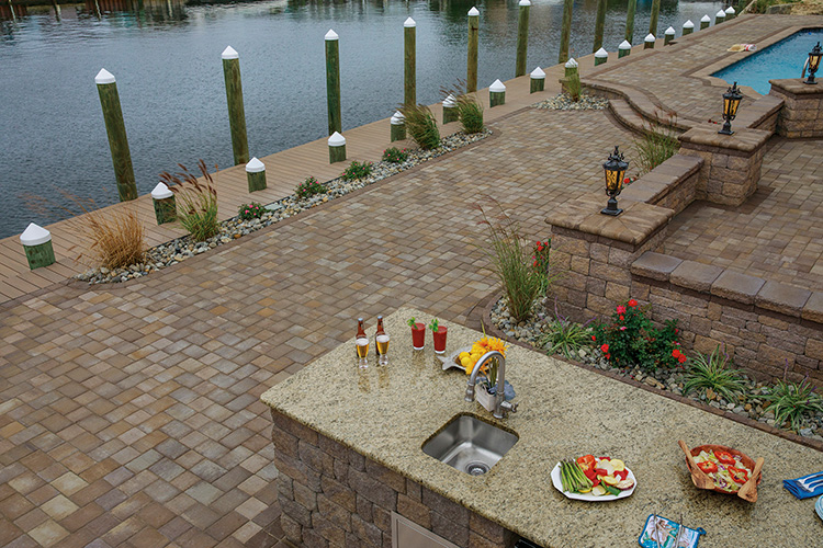 Custom paver patio and outdoor kitchen with a granite countertop and built-in sink overlooking a canal in Selbyville, Delaware.