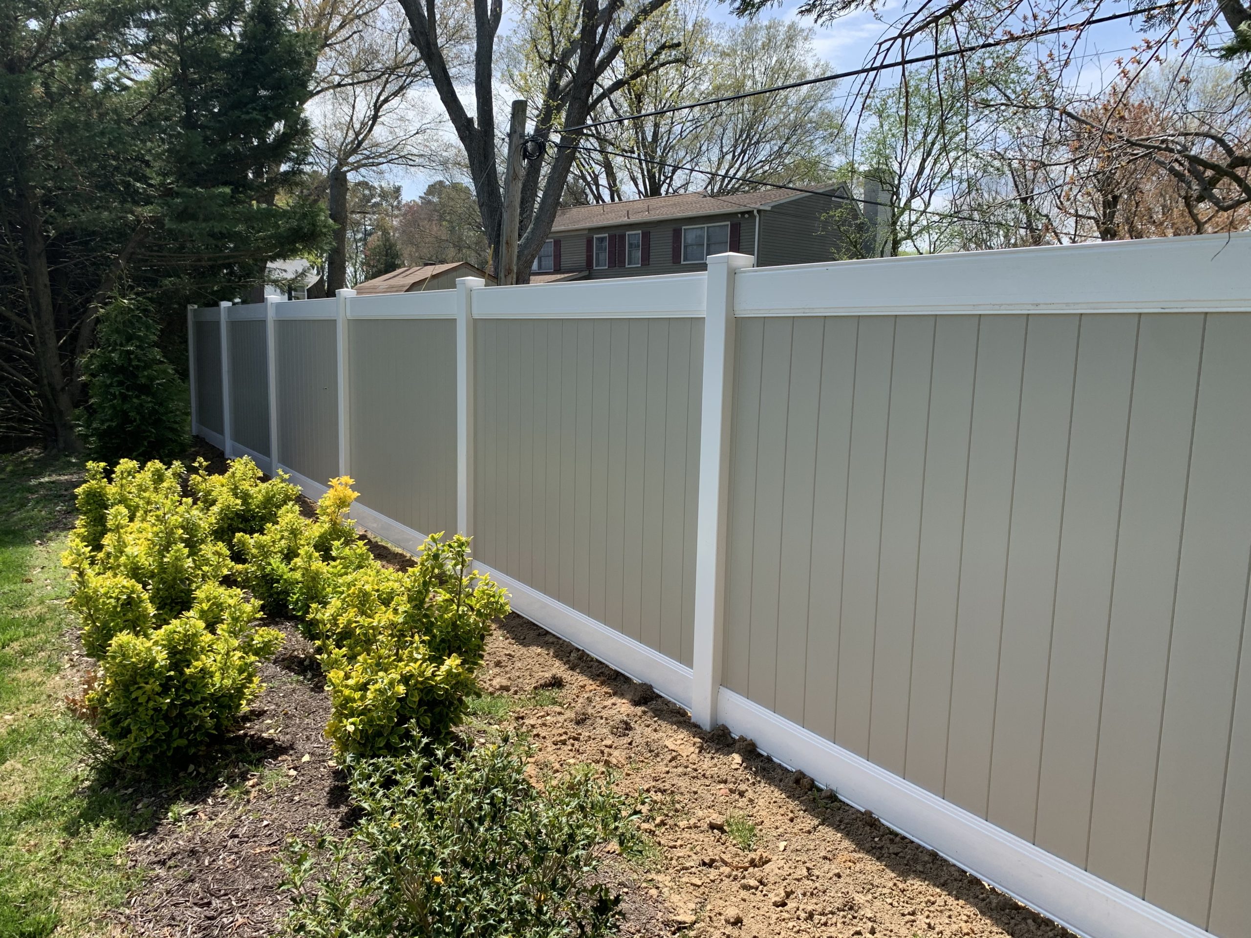 Modern two-tone privacy fence featuring white vinyl panels and a black aluminum frame installed in a residential backyard.